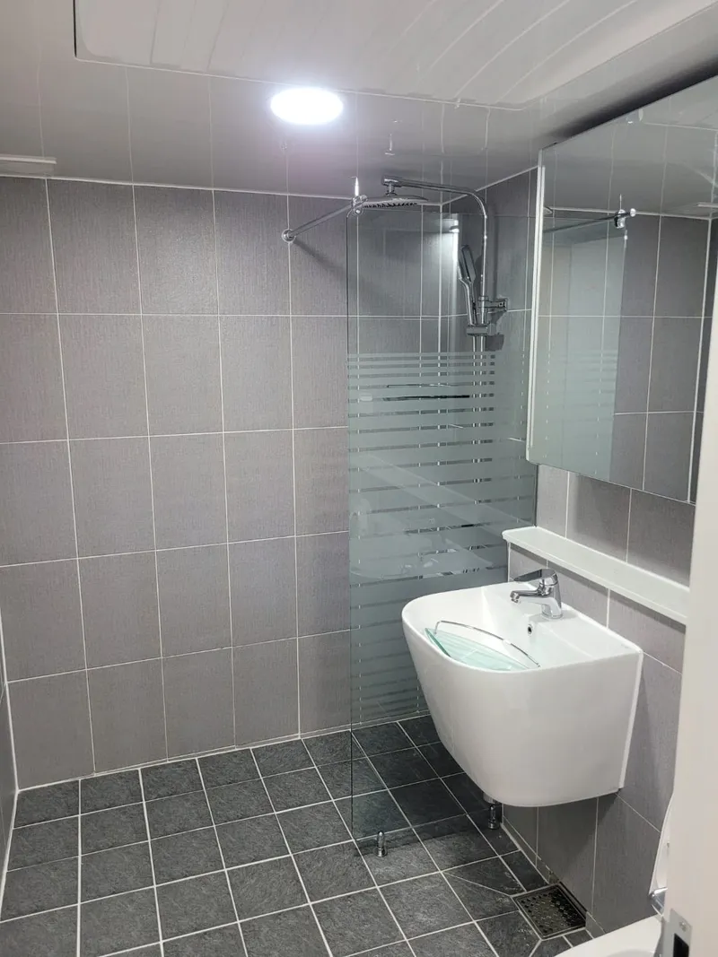 유리 칸막이를 세운 회색 타일 욕실